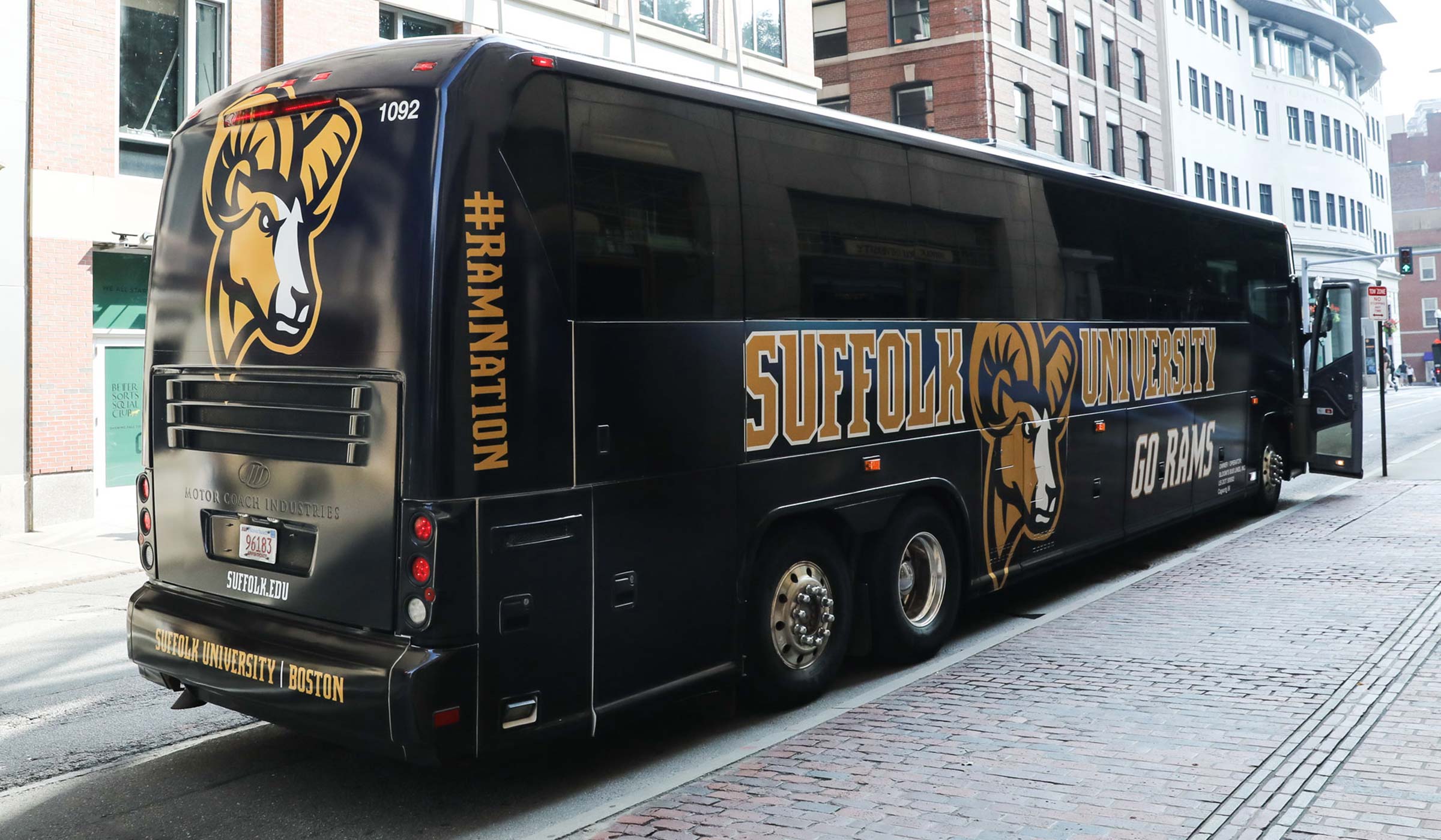 branded bus with Suffolk University and Go Rams and the ram logo on the side in front of 73 Tremont Street
