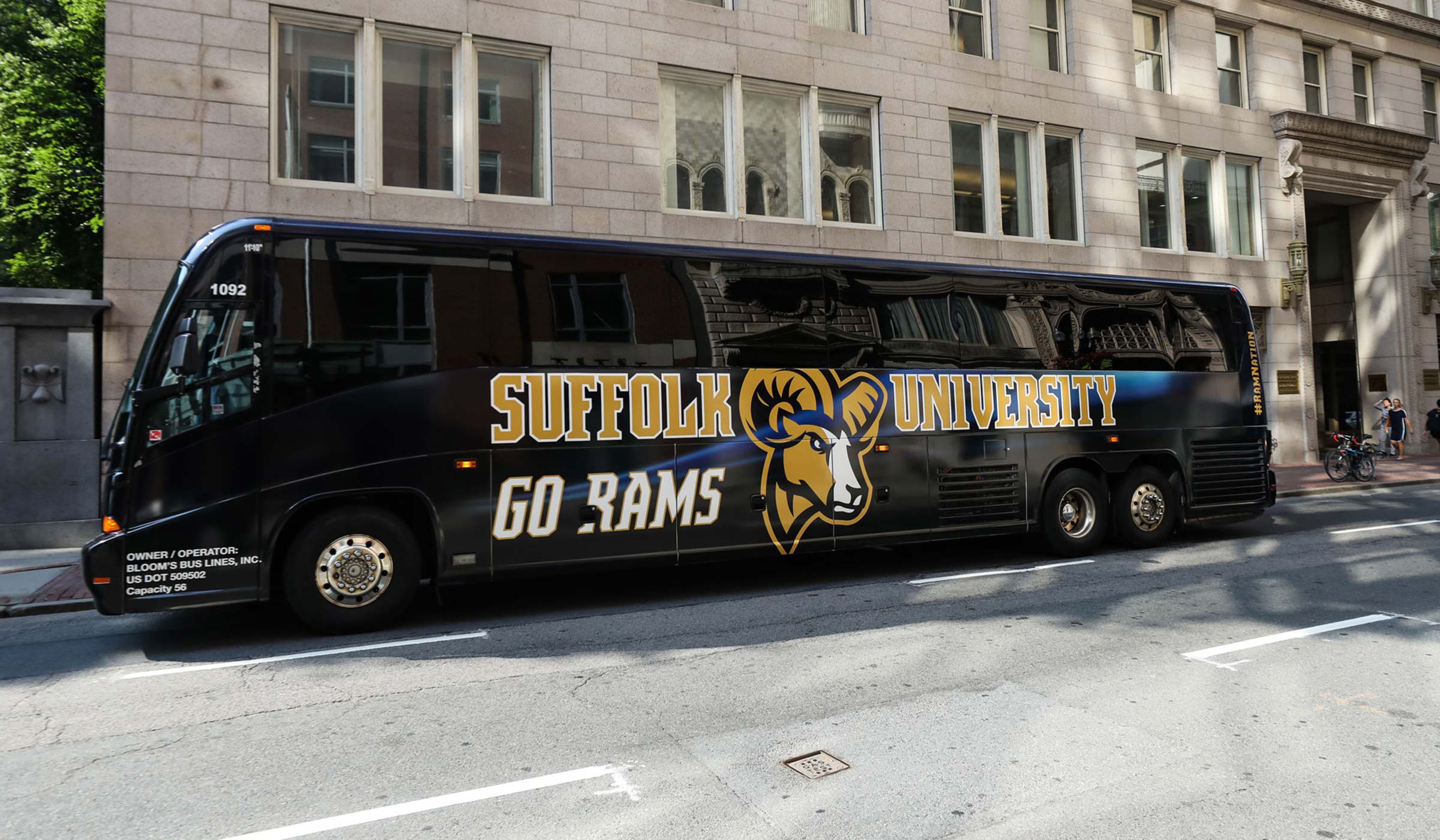 branded bus with Suffolk University and Go Rams and the ram logo on the side in front of 73 Tremont Street